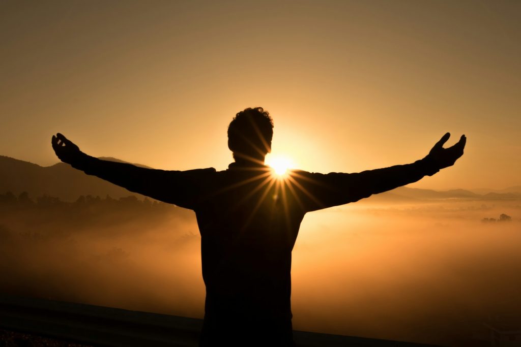Silhouet met open armen bij zonsopkomst, jezelf durven zijn