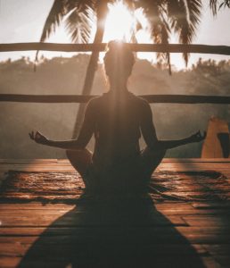 Vrouw in meditatie bij zonsondergang
