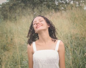 Vrouw glimlacht met gesloten ogen in een veld