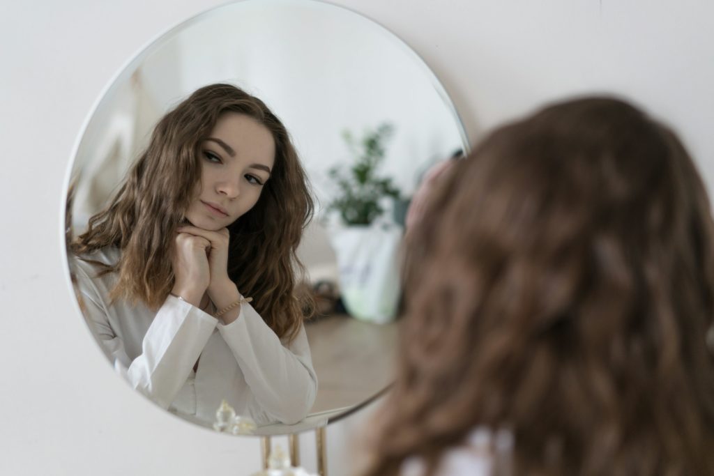 Vrouw kijkt rustig naar haar spiegelbeeld
