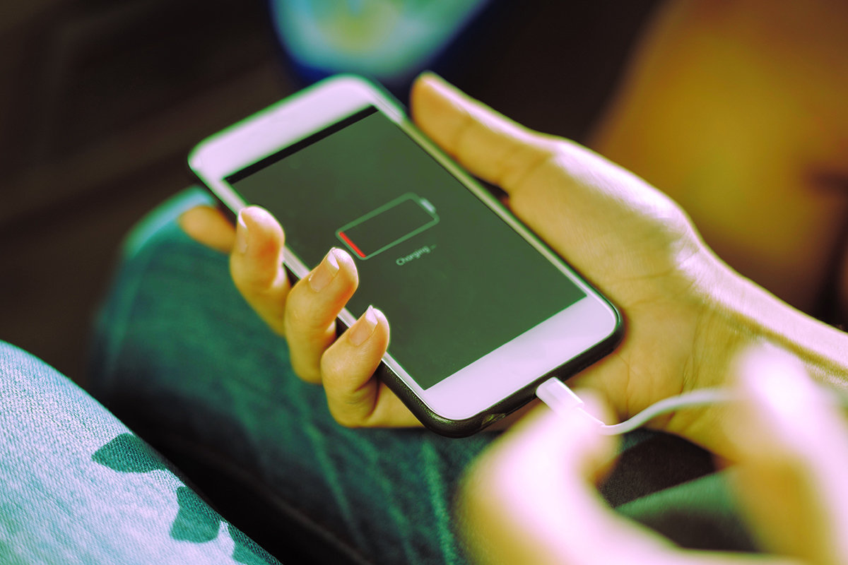 Telefoon met lege batterij die wordt opgeladen, metafoor voor rust nemen en weer opladen