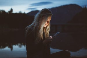 Vrouw kijkt naar haar telefoon in schemerlicht