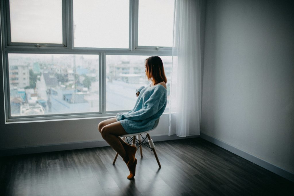 Vrouw zit op een stoel bij het raam