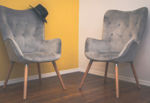 Twee stoelen tegenover elkaar tegen een gele muur