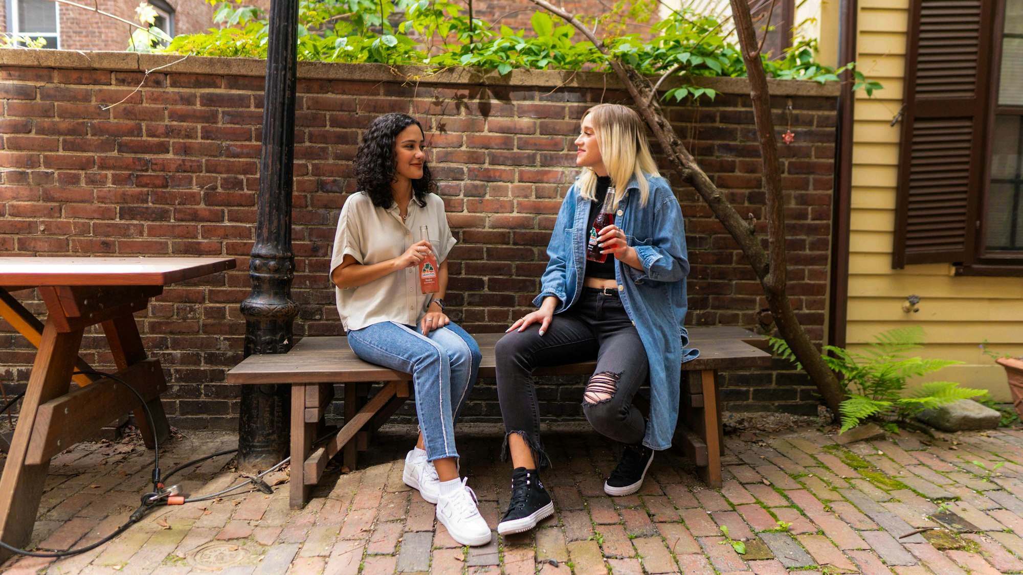 Twee vrouwen zitten op een bankje in een binnentuin te praten