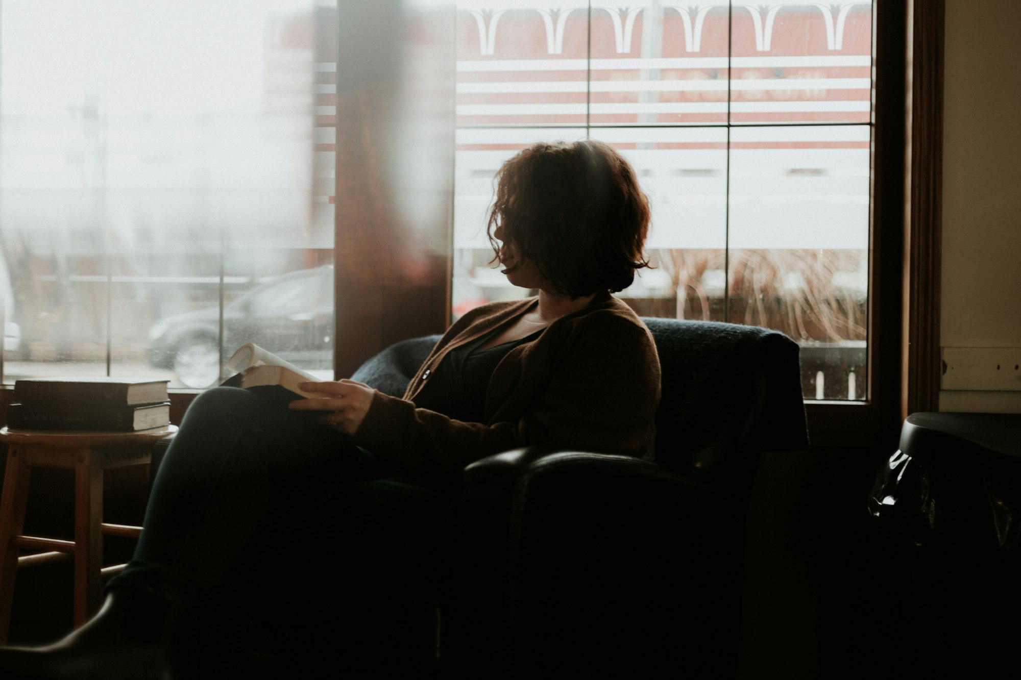 Vrouw leest in een stoel bij het raam, alleen met haar gedachten