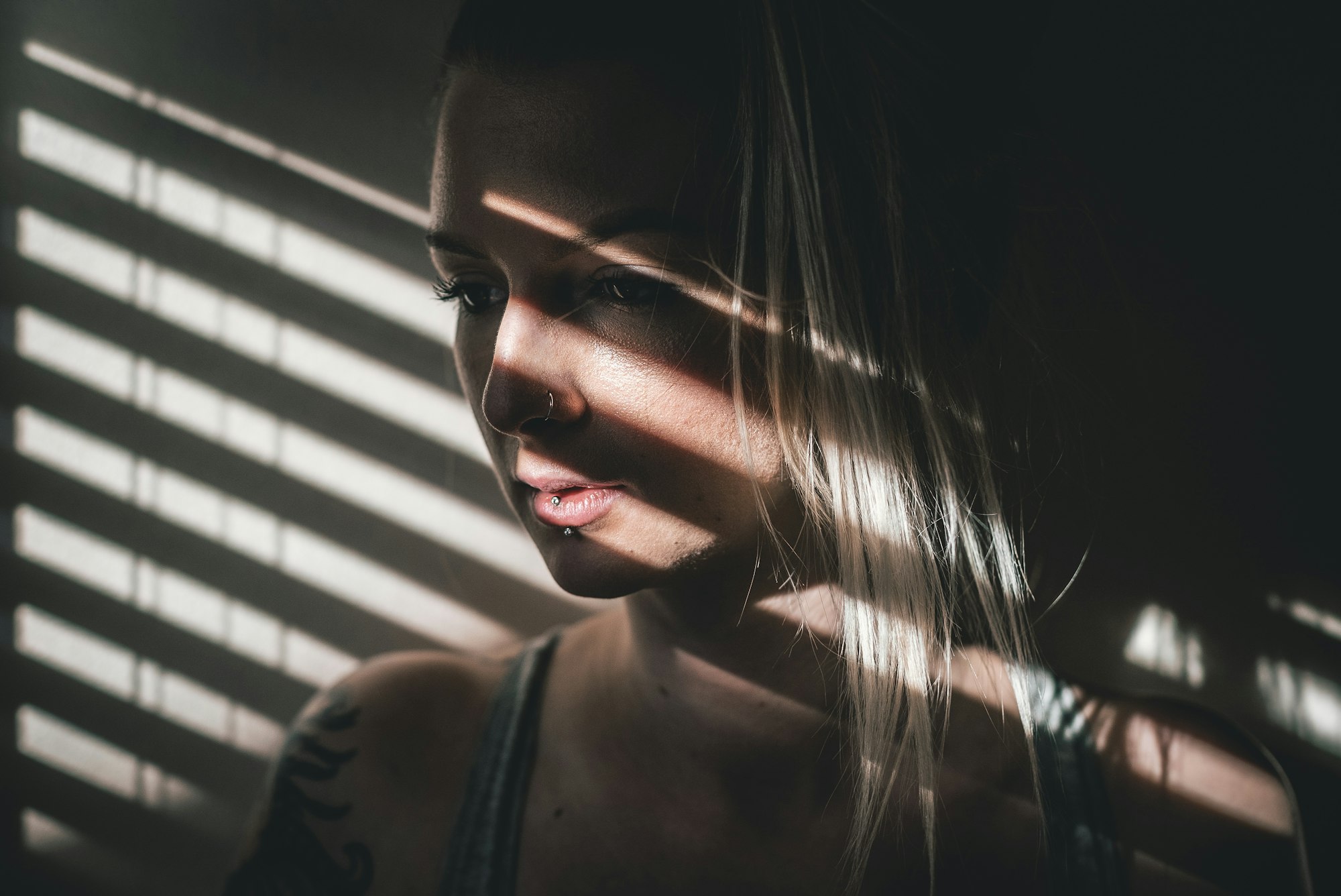 Vrouw met de schaduw van jaloezielatten over haar gezicht, half afgewend