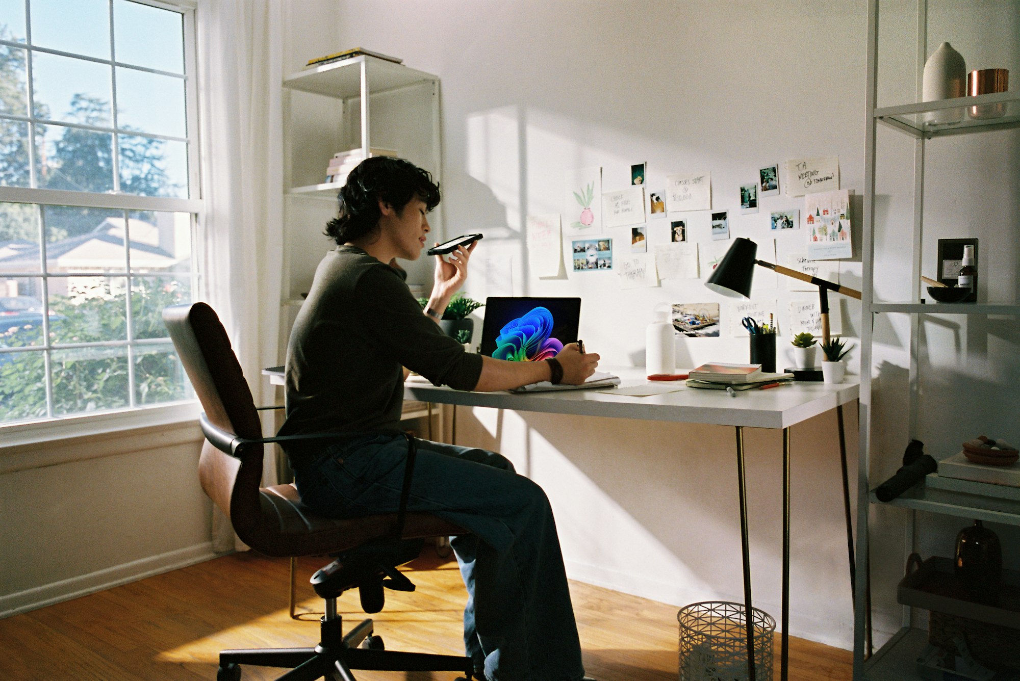 Vrouw werkt aan een bureau in een lichte kamer met grote ramen