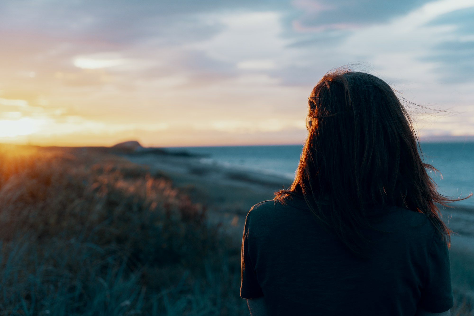 Vrouw kijkt uit over zee bij zonsopgang