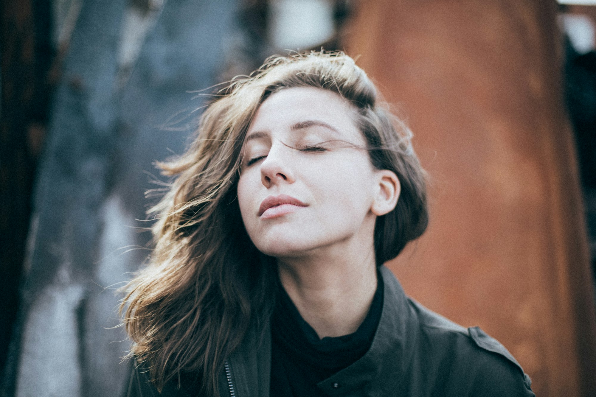 Vrouw met gesloten ogen en haar in de wind, gezicht naar het licht
