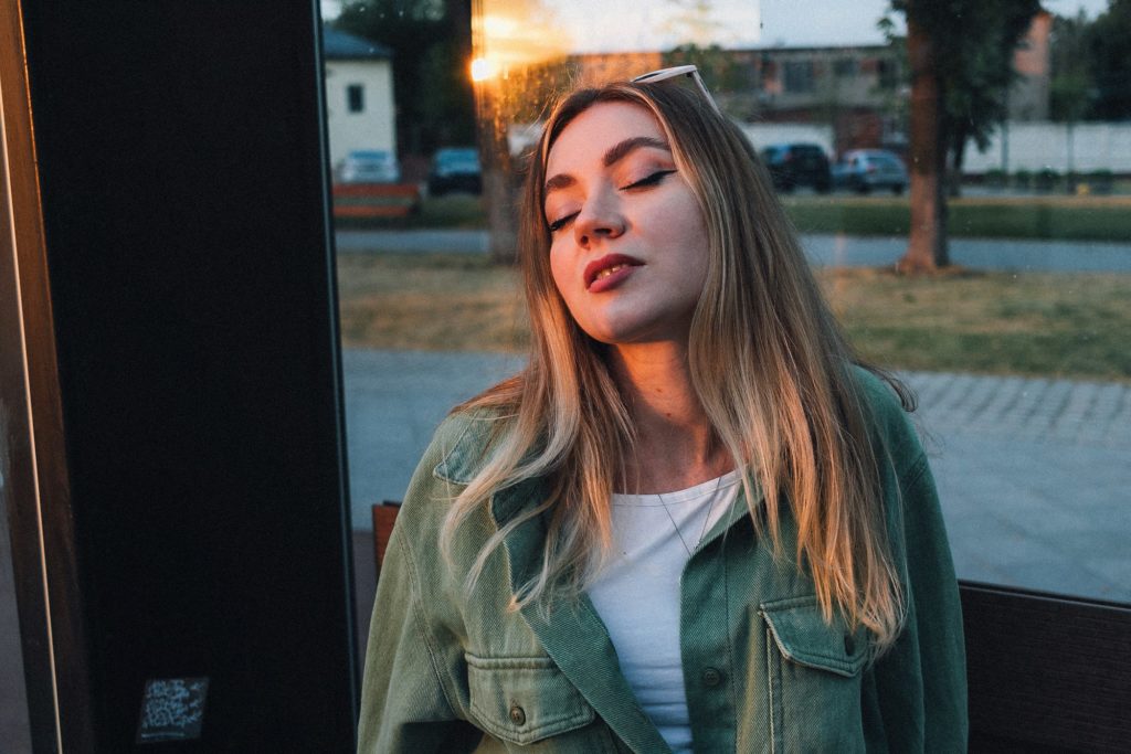 Vrouw met gesloten ogen in het late zonlicht op een plein
