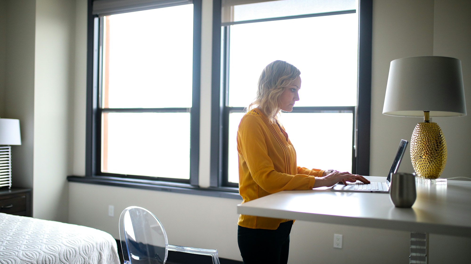 Vrouw staat te werken aan een sta-bureau bij een groot raam