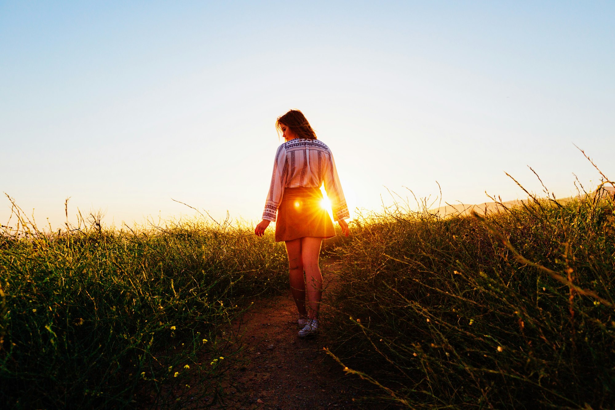 Vrouw loopt een pad omhoog het licht in bij zonsondergang