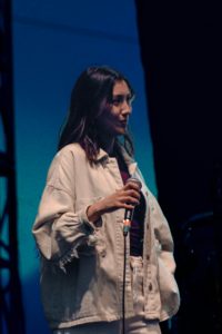 Vrouw met een microfoon in haar hand op een podium
