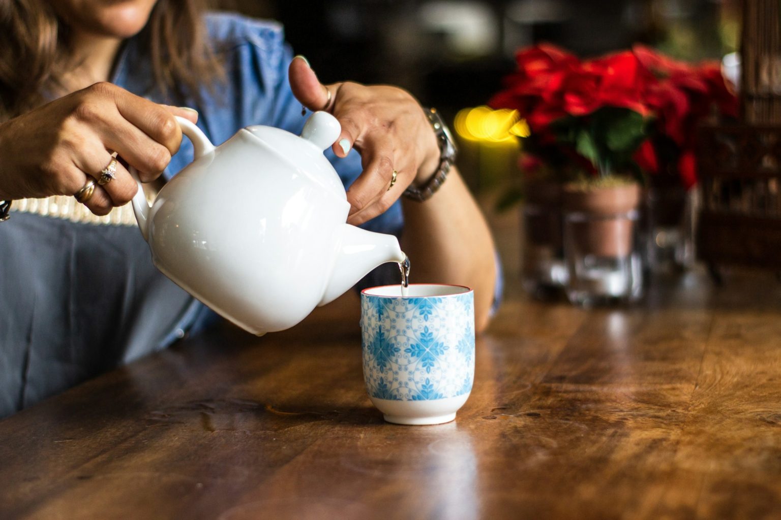 Vrouw schenkt thee in aan een houten tafel