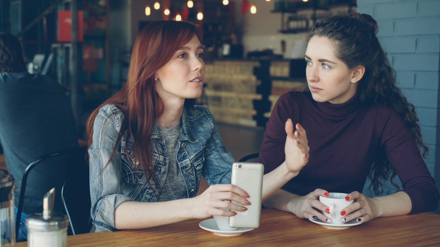 Twee vrouwen in gesprek aan een cafétafel