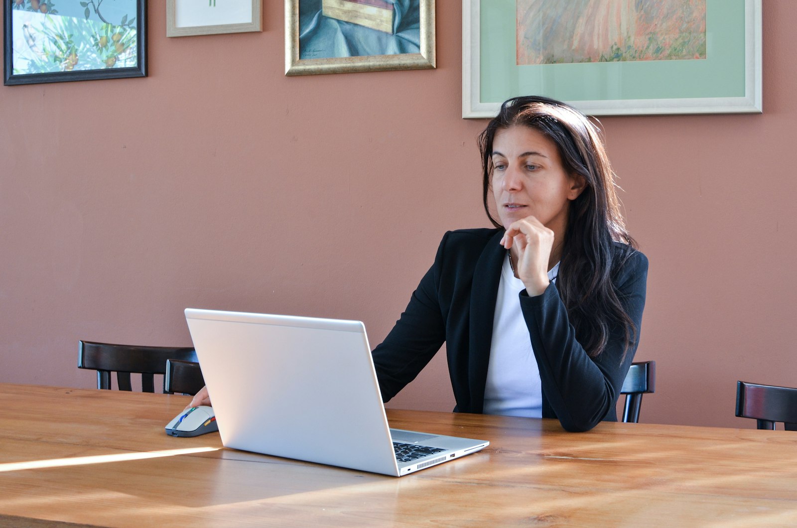 Vrouw zit nadenkend achter haar laptop