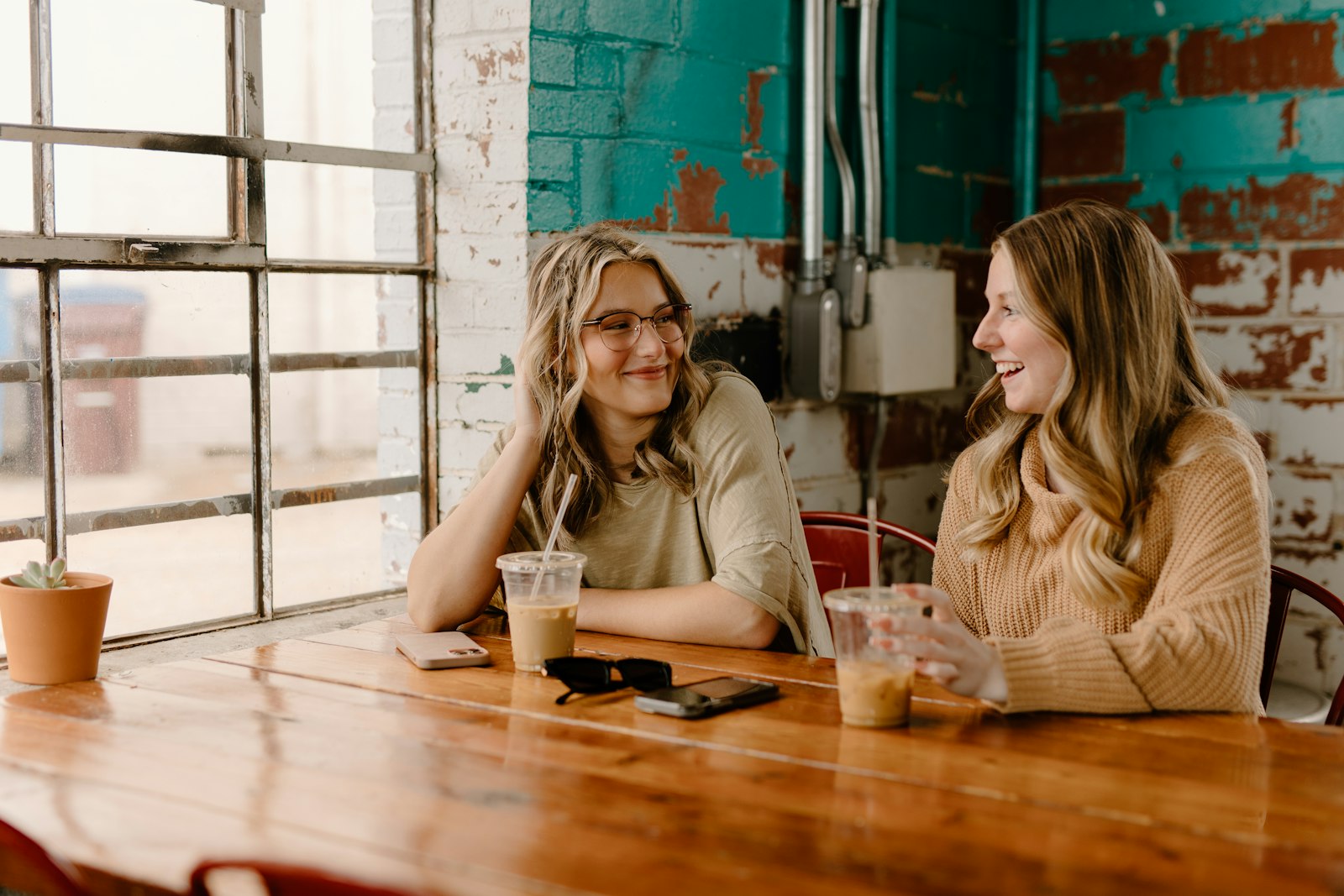 Twee vrouwen in gesprek aan een houten tafel