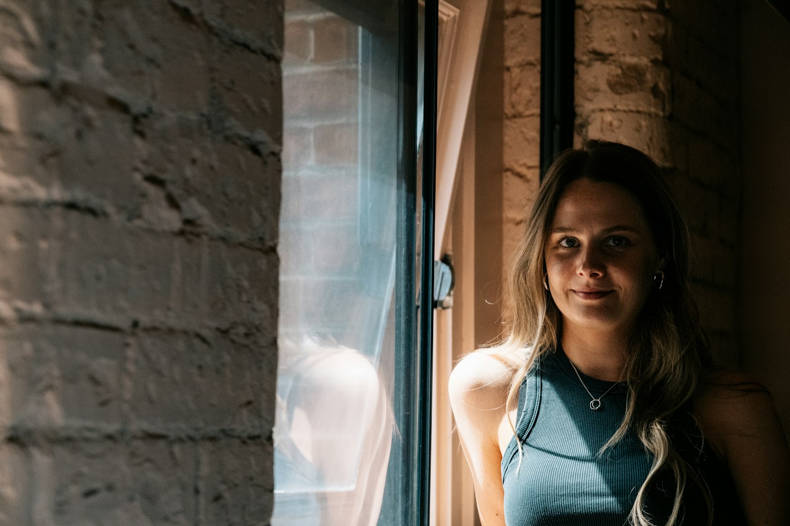 Vrouw kijkt zelfverzekerd in de camera bij een zonnig raam