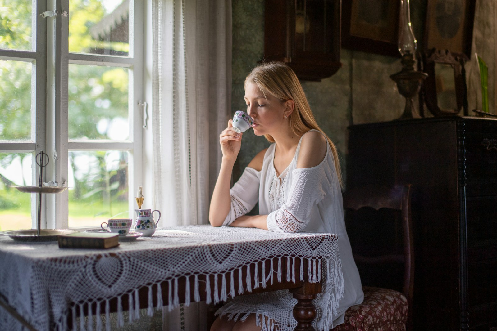 Vrouw drinkt rustig thee bij het raam in het ochtendlicht