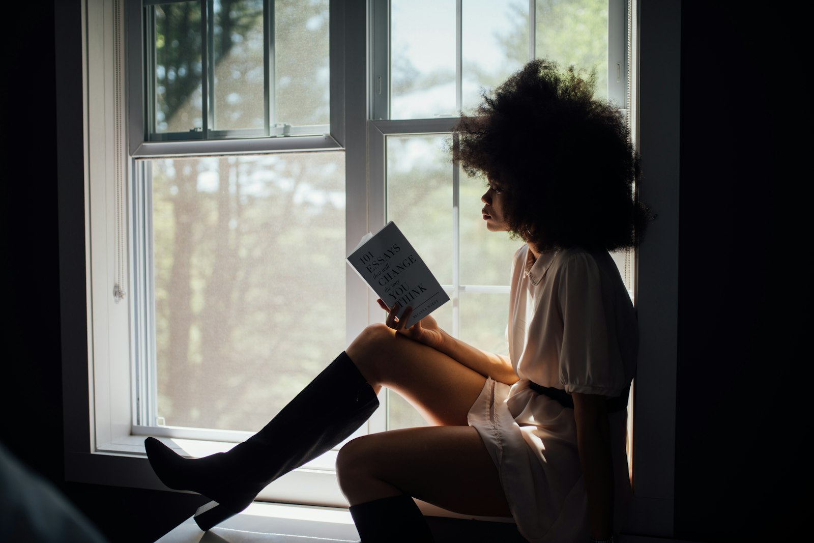 Vrouw leest een boek in de vensterbank bij het licht