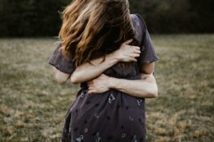 Vrouw slaat haar armen om zichzelf heen in een veld