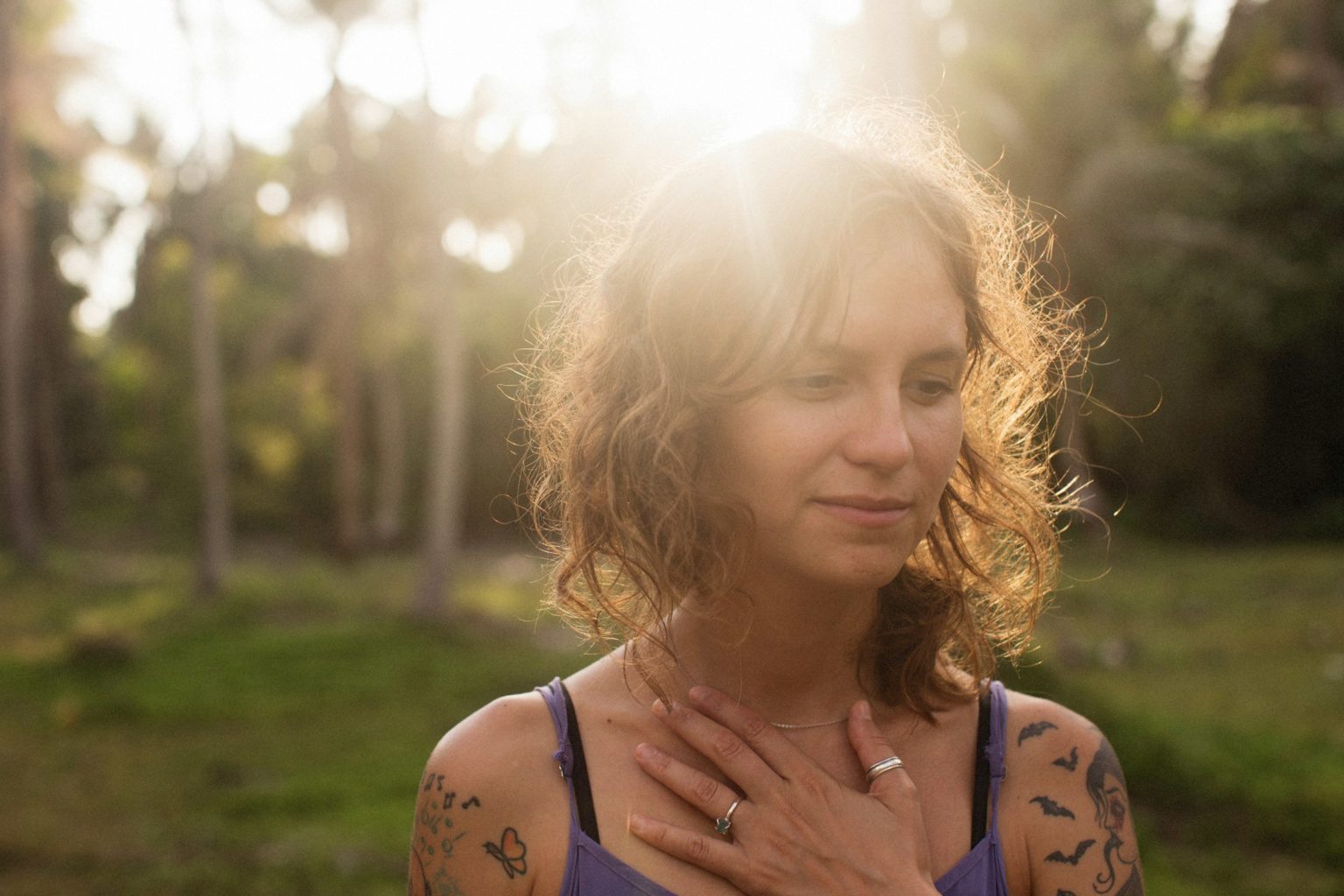 Vrouw in de zon met haar ogen dicht en haar hand op haar borst