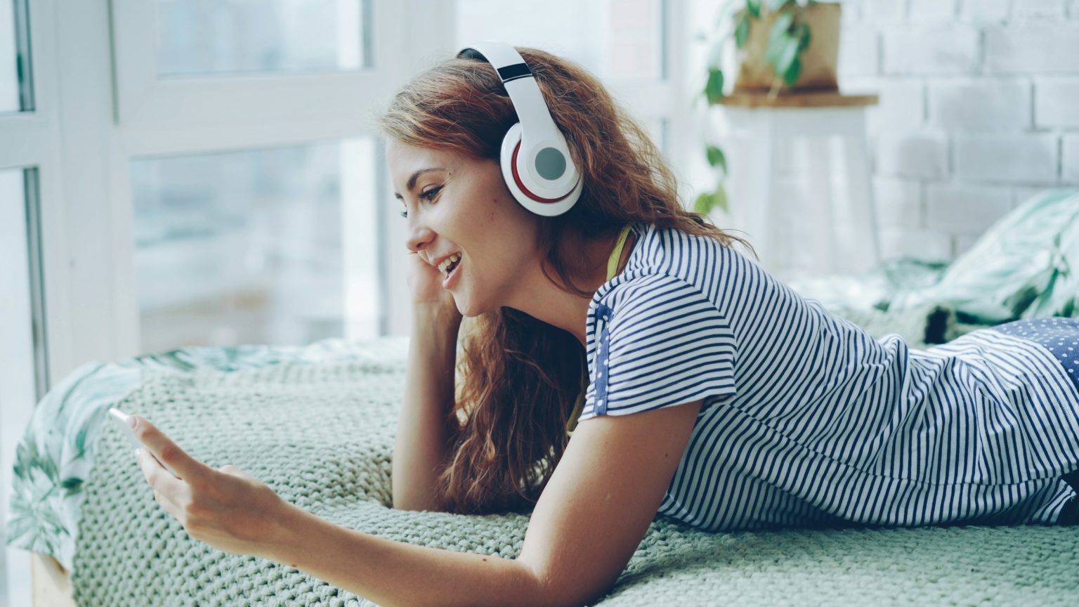 Vrouw met koptelefoon ligt ontspannen op bed