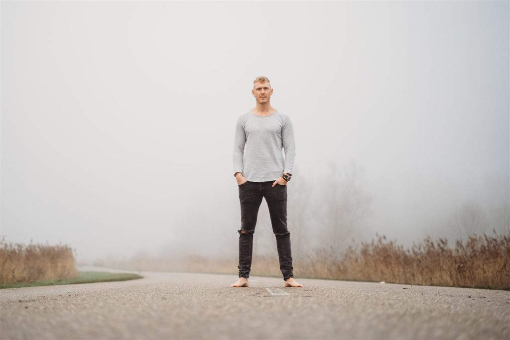 Jonathan Bouter staat blootsvoets op een lege weg in de mist