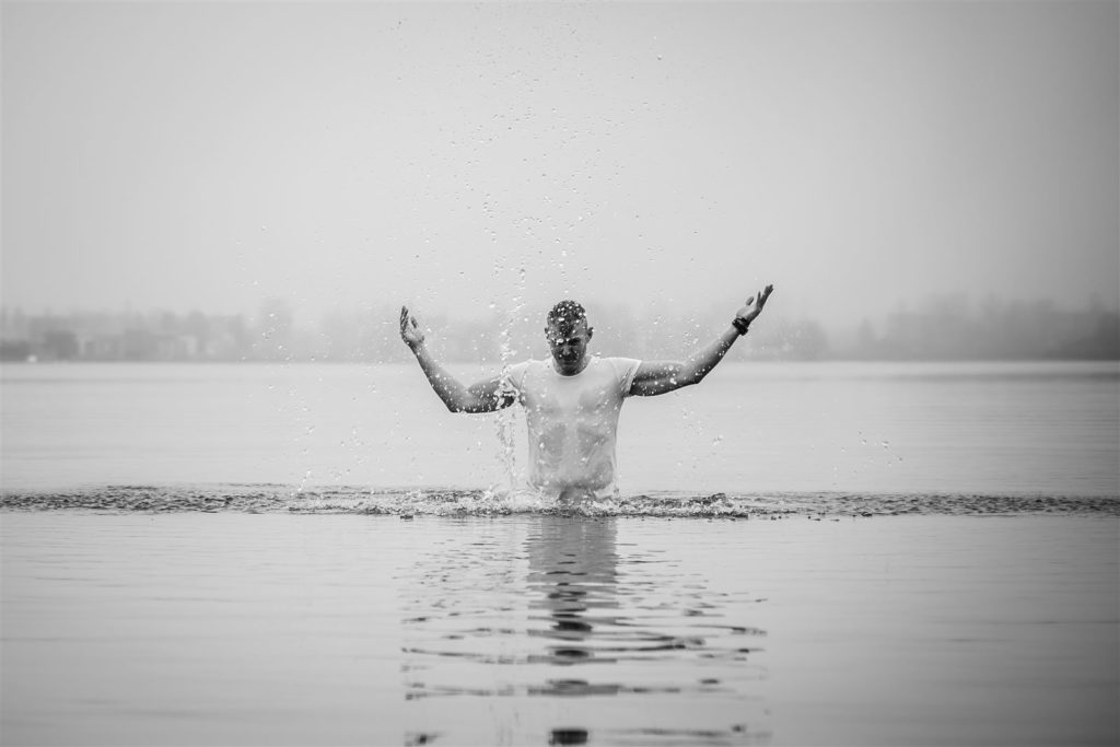 Jonathan Bouter staat in het water en spreidt zijn armen terwijl het water opspat