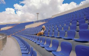 Vrouw zit alleen op de tribune van een leeg stadion