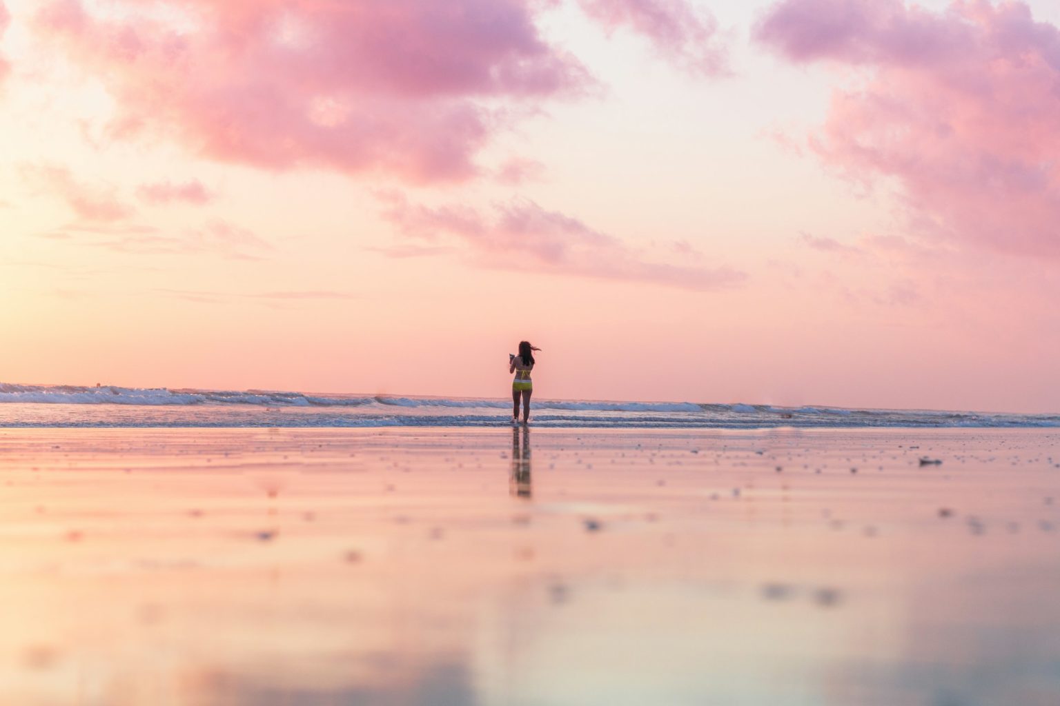 Vrouw alleen op een rustig strand bij zonsopkomst