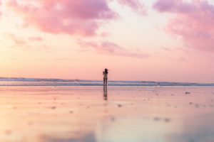 Vrouw alleen op een rustig strand bij zonsopkomst