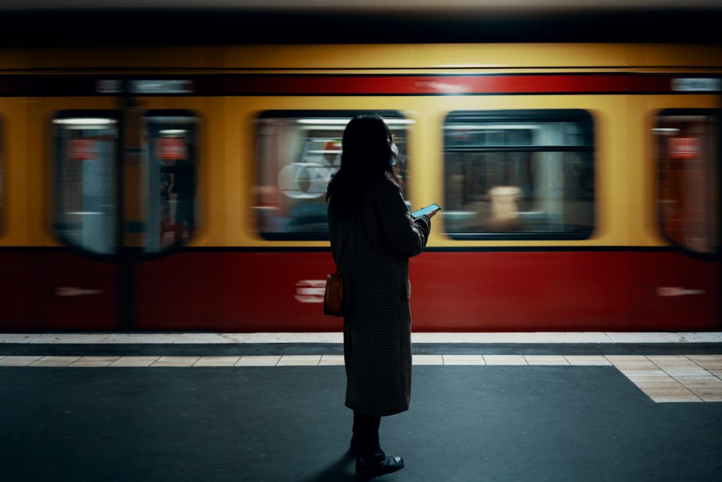 Vrouw staat op het perron terwijl de trein voorbijraast