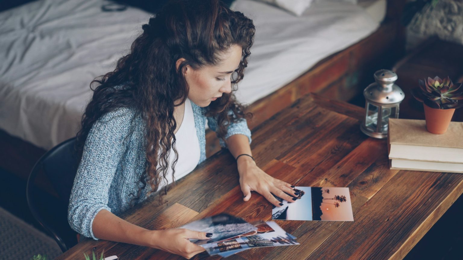 Vrouw bekijkt oude foto's aan een houten tafel