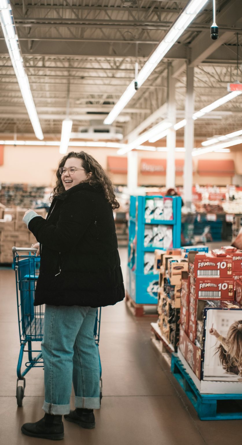 Lachende vrouw met een winkelwagen in de supermarkt
