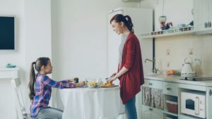 Moeder in de keuken met haar dochter aan tafel