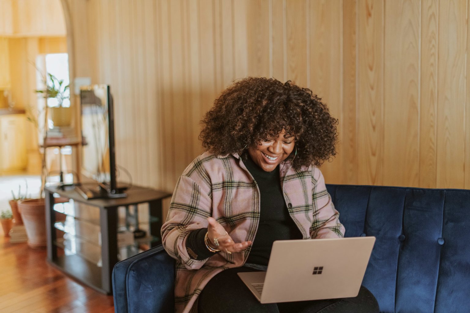 Vrouw thuis op de bank met haar laptop, in gesprek tijdens een online sessie