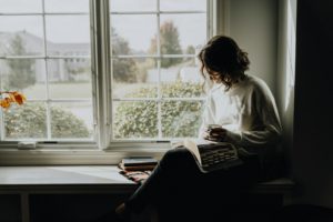Vrouw schrijft in haar dagboek bij het raam